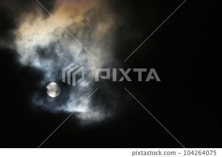 Sun disk behind backlit clouds 104264075
