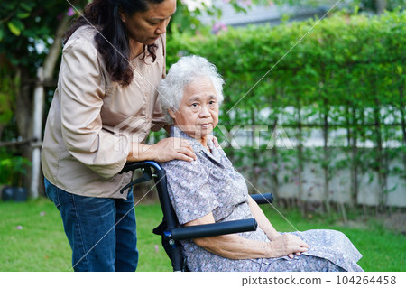 Caregiver help Asian elderly woman disability patient sitting on wheelchair in park, medical concept. 104264458