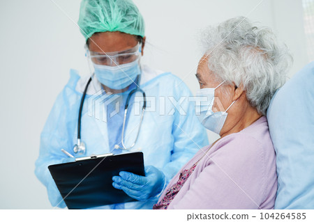 Doctor in ppe user infrared thermometer to check temperature of asian elderly woman patient for safety to protect covid 19 virus. 104264585