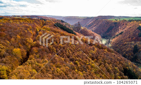 fall autumn aerial view rock with medieval castle Ehrenburg on it near moselle river in Brodenbach with forest hills 104265071