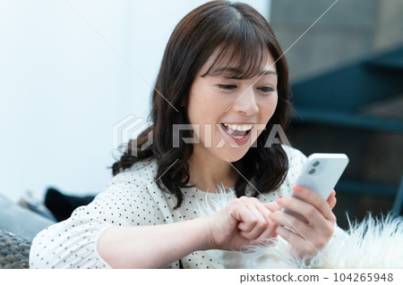Middle-aged woman using a smartphone on the sofa Middle-aged woman using a smartphone on the sofa 104265948