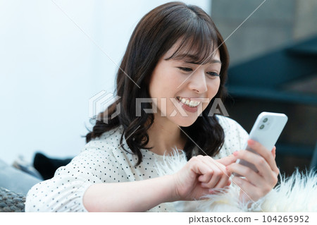 Middle-aged woman using a smartphone on the sofa 104265952