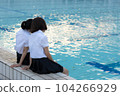 High school girls hugging each other by the pool at sunset 104266929