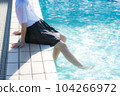 A high school girl wearing a uniform and putting her feet in the pool 104266972