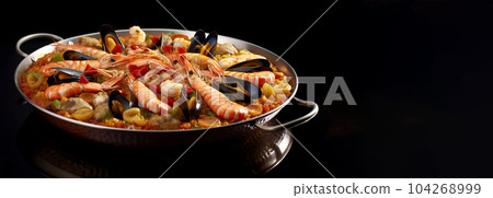 Large skillet with delicious paella on dark background, restaurant concept, healthy food 104268999