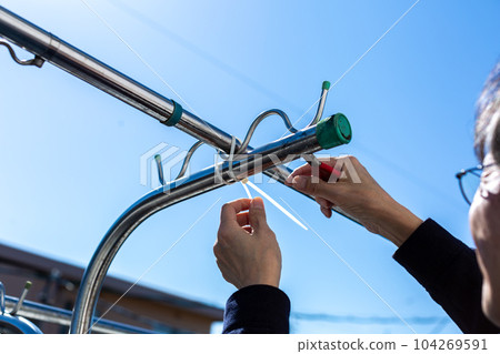 A man taking care of a clothesline on the balcony 104269591
