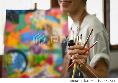 Select focus on hand of artist holding paintbrushes standing in art studio. Art, hobby and leisure activity concept 104270783