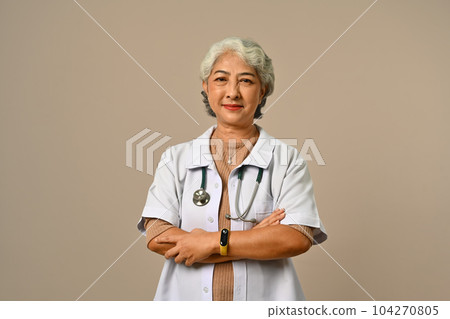 Confident senior woman doctor dressed in white overall with stethoscope isolated on brown background 104270805