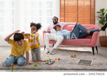 Children play with wooden toy on floor in living room while parent sitting on couch. Two kids playing with colorful blocks... Children play with wooden toy on floor in living room while parent sitting on couch. Two kids playing with colorful blocks... 104270828