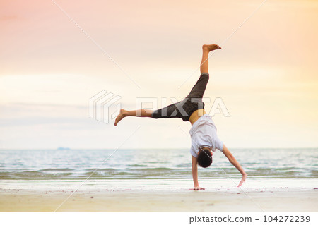 Teenager doing calisthenics exercise. Beach yoga. 104272239