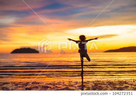 Child playing on ocean beach. Kid at sunset sea. Child playing on ocean beach. Kid at sunset sea. 104272351