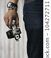 Right hand holding camera with watch and bracelet 104272711