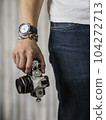 Right hand holding camera with watch and bracelet 104272713