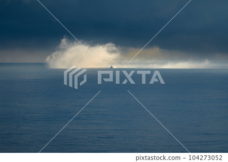 A boat on the ocean emerges from a cloud of mist on the ocean A boat on the ocean emerges from a cloud of mist on the ocean 104273052