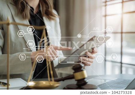 Judge in a courtroom using laptop and tablet with AML anti money laundering icon on virtual screen. Judge in a courtroom using laptop and tablet with AML anti money laundering icon on virtual screen. 104273328