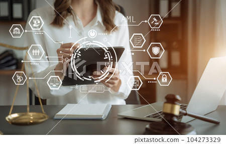 Judge in a courtroom using laptop and tablet with AML anti money laundering icon on virtual screen. 104273329