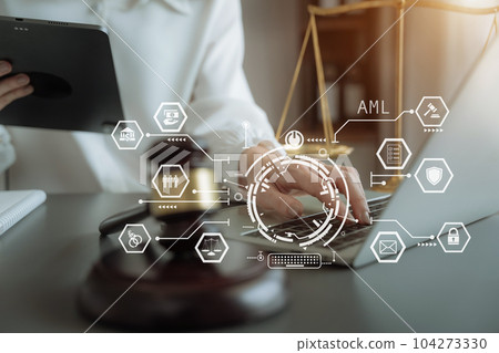 Judge in a courtroom using laptop and tablet with AML anti money laundering icon on virtual screen. 104273330