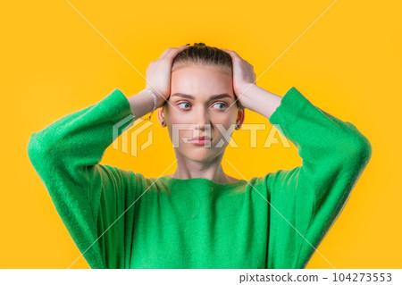 Woman afraid of something, she in shock on yellow backdrop.Holding head 104273553