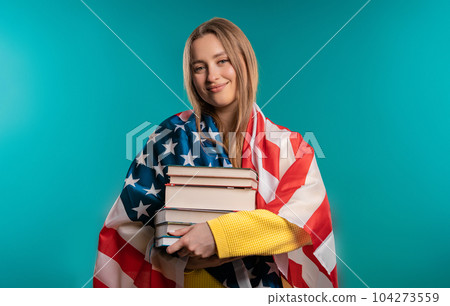 American woman student holds stack of university books, college library on blue 104273559
