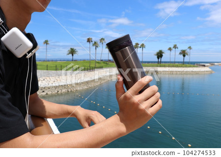 Refreshing man by the sea with a water bottle Refreshing man by the sea with a water bottle 104274533