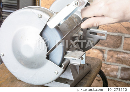 Knife sharpener and hand with blade on table, closeup 104275250