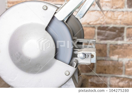 Knife sharpener and hand with blade on table, closeup 104275280