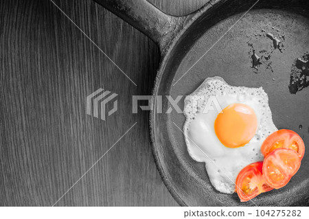 Egg, sunny side up, with fresh tomatoes in a frying pan 104275282