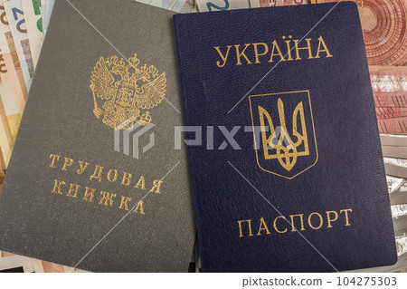 Ukrainian passport and Russian workbook against the background of euro bills Ukrainian passport and Russian workbook against the background of euro bills 104275303