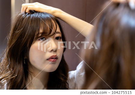 年輕女子在鏡子裡檢查自己的髮型 104275515