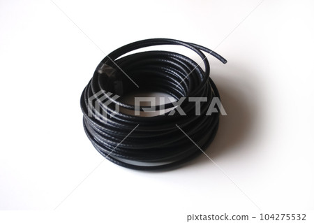 An isolated black rolled electric cable against a white background. This electrical cable represents the essential connection for energy and technology equipment. Out of focus An isolated black rolled electric cable against a white background. This electrical cable represents the essential connection for energy and technology equipment. Out of focus 104275532