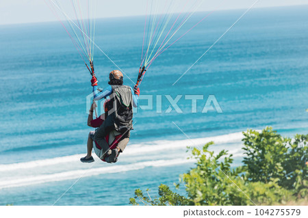 Paraglider flies in front of the ocean Paraglider flies in front of the ocean 104275579