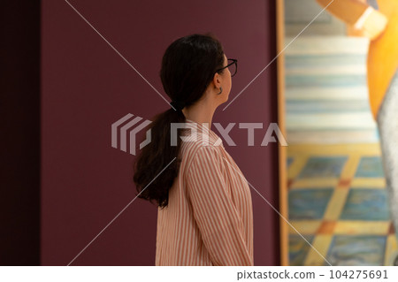 Back view of woman guide looking at masterpiece in exhibition. Concept of Museum Day and cultural education Back view of woman guide looking at masterpiece in exhibition. Concept of Museum Day and cultural education 104275691