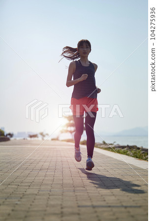 young asian adult woman running jogging outdoors in seaside park young asian adult woman running jogging outdoors in seaside park 104275936