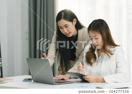 Two professional millennial Asian startup businesspeople are discussing evaluation data in a conference room, focusing on growth and pointing to a financial account chart,graph. 104277338