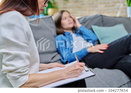 Close-up of female psychologist's hands with clipboard making notes, in therapy Close-up of female psychologist's hands with clipboard making notes, in therapy 104277654