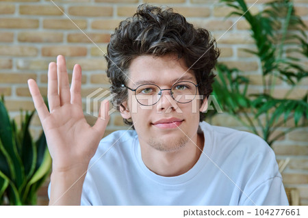 Headshot portrait of young student guy in glasses waving hello Headshot portrait of young student guy in glasses waving hello 104277661