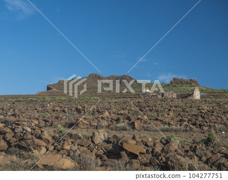 Abandoned ruins of farm house at flat plateau on top of La Merica mountain with cacti, stones and sea view. valle Gran Rey, La Gomera, Canary Islands. Copy space. 104277751