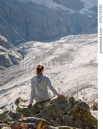 Hiker woman relaxing on stone near the mountains with glacier 104278361