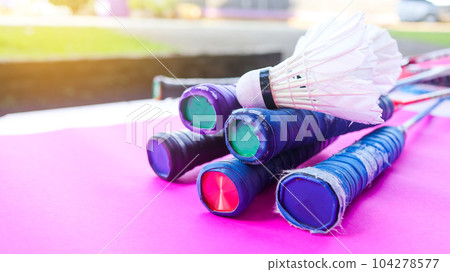 White badminton shuttle cocks and rackets handles on pink background 104278577