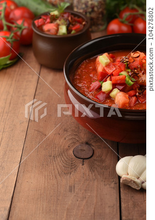 Traditional spanish cold gazpacho tomato soup on wood background with place for text. Ingredients around the cooked soup. Recipe, menu. Vegetarian healthy food. Traditional spanish cold gazpacho tomato soup on wood background with place for text. Ingredients around the cooked soup. Recipe, menu. Vegetarian healthy food. 104278802