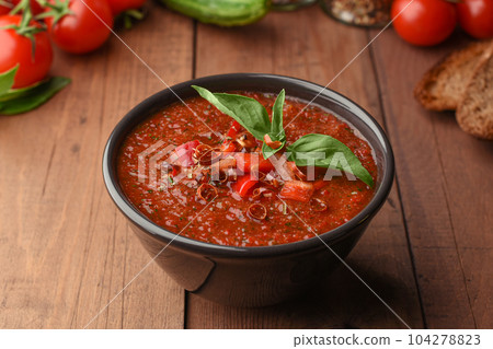Vegetarian organic soup gazpacho on wooden background. Cold summer tomatoes soup with pepper, bread croutons cucumber and basil. Copy space on Wood background. Vegetarian organic soup gazpacho on wooden background. Cold summer tomatoes soup with pepper, bread croutons cucumber and basil. Copy space on Wood background. 104278823