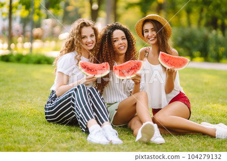 Three young woman have fun together and eating watermelon in hot summer day. Three young woman have fun together and eating watermelon in hot summer day. 104279132