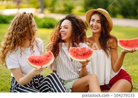 Three young woman have fun together and eating watermelon in hot summer day. Three young woman have fun together and eating watermelon in hot summer day. 104279133