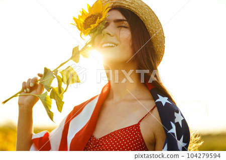 Beautiful girl in hat with the American flag in a sunflower field. 4th of July. Fourth of July. Freedom Beautiful girl in hat with the American flag in a sunflower field. 4th of July. Fourth of July. Freedom 104279594