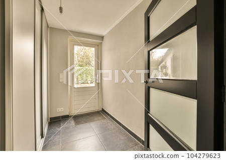 a hallway in a house with white walls and black trim on the door, there is an entry way that leads to another room a hallway in a house with white walls and black trim on the door, there is an entry way that leads to another room 104279623