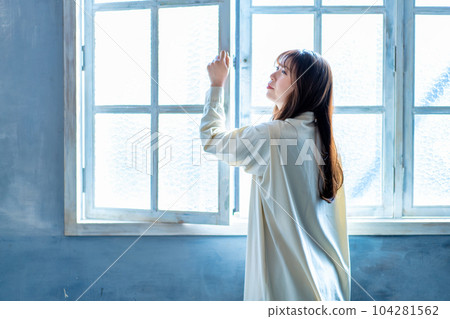 A woman who opens the window and bathes in the sun 104281562