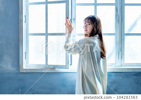 A woman who opens the window and bathes in the sun 104281563