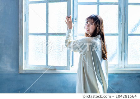 A woman who opens the window and bathes in the sun 104281564