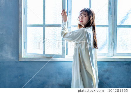 A woman who opens the window and bathes in the sun 104281565