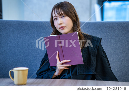 A woman reading a book at a cafe 104281946